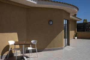 a table and chairs on a patio with a clock on a building at Hotel Kore in Villaggio Mosè