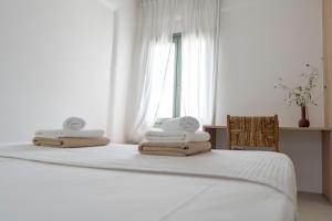 a white bedroom with a bed with towels on it at Tzitziki in Piso Livadi +20 photos