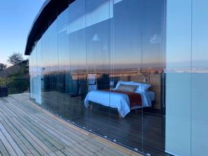 a bedroom with a bed on a balcony with glass walls at Apalta Vista Wine Lodge in Estación Santa Cruz +10 photos