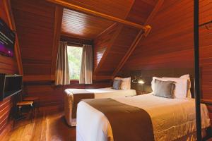 two beds in a room with wood paneled walls at DOM Hotel in Campos do Jordão