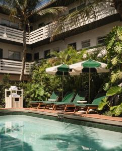 a swimming pool with chairs and umbrellas next to a building at Perroquet Hotel in Fort Lauderdale