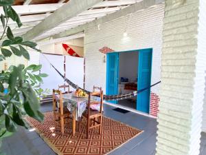 a porch with a table and chairs and a blue door at Pousada 3 Abelhas in Caucaia