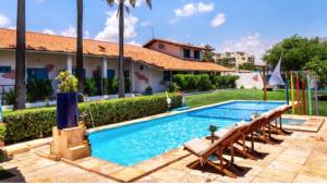 a large swimming pool with benches next to a house at Pousada 3 Abelhas in Caucaia