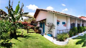 a white house with a yard with plants at Pousada 3 Abelhas in Caucaia