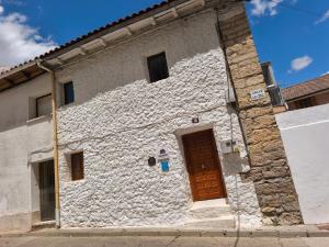 a white stone building with a brown door at Casa Nentis in Mucientes +4 photos