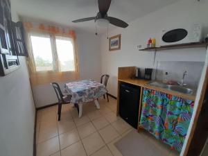 a kitchen with a table and a table and a ceiling fan at Fare Arana Mooréa Guesthouse in Atiha