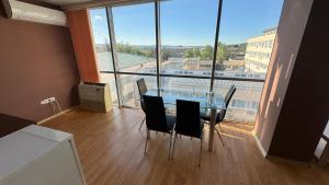 a glass table and chairs in a room with a large window at Апартамент 503 in Samokov