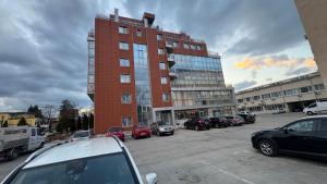 a tall red brick building with cars parked in a parking lot at Апартамент 503 in Samokov