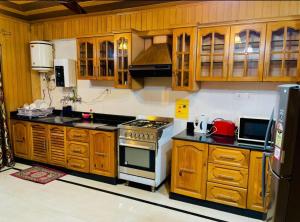 a kitchen with wooden cabinets and a stove top oven at Zakiyas Homestay in Srinagar +4 photos