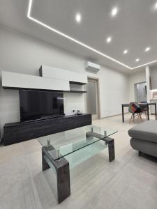 a living room with a glass coffee table and a tv at Mirabaia in Bacoli