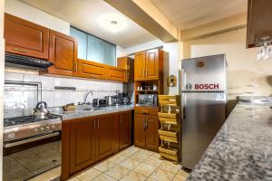 a kitchen with wooden cabinets and a stainless steel refrigerator at El Balcón del Sol - Dpto Céntrico con Vistas Perfectas in Cusco