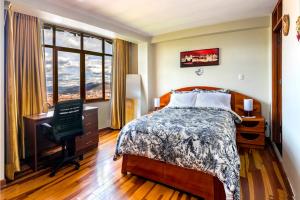 a bedroom with a bed and a desk and a window at El Balcón del Sol - Dpto Céntrico con Vistas Perfectas in Cusco