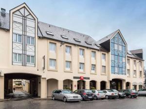a large building with cars parked in a parking lot at ibis Alençon in Alençon