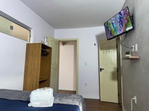 a room with a bed and a flat screen tv at Studios Caripunas Reformado Localização Central in Belém