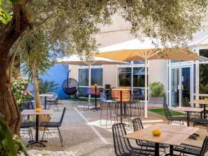 an outdoor patio with tables and chairs and an umbrella at ibis Styles Perpignan Centre Gare in Perpignan