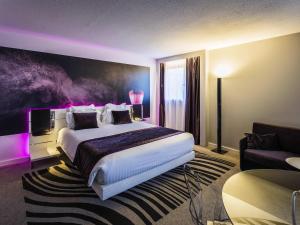 a hotel room with a large bed and a couch at Novotel Orléans Saint Jean de Braye in Saint-Jean-de-Braye +127 photos