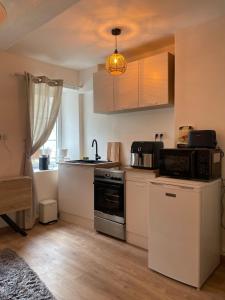 a small kitchen with a stove and a microwave at Studio de caractère en pierre in Coutances