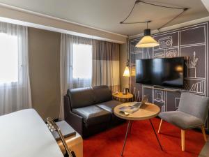 a hotel room with a bed and a couch and a tv at ibis Le Havre Centre in Le Havre
