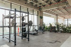 a gym with lots of equipment in a room with windows at Wake Living in Medellín +7 photos