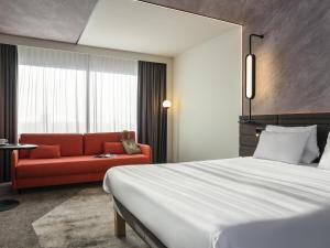 a hotel room with a bed and a red couch at Novotel Rotterdam Brainpark in Rotterdam