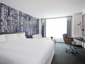 a hotel room with a large bed and a desk at Novotel Montreal Center in Montreal +56 photos
