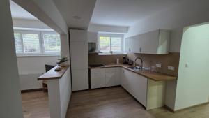 a kitchen with white cabinets and a sink at Apartmán U splavu Luhačovice in Luhačovice +11 photos