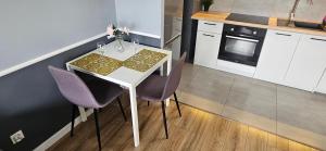 a kitchen with a white table and purple chairs at Andersena 43 Ząbki in Ząbki +11 photos