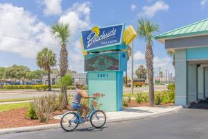 a woman riding a bike in front of a gas station at Beachside Hotel & Suites Cocoa Beach - Port Canaveral in Cocoa Beach