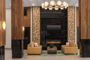 a lobby with a fireplace and two chairs and a tv at Le Parc Gatineau, Tapestry Collection by Hilton in Gatineau