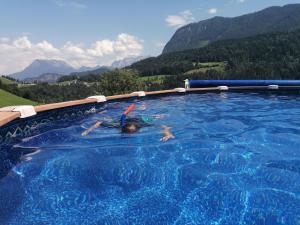 a person in a swimming pool with mountains in the background at Wanishof in Thiersee