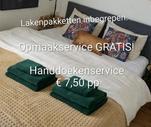 a bed with green towels sitting on top of it at JOY Boutique Chalet Berkhout - Hoorn in De Hulk