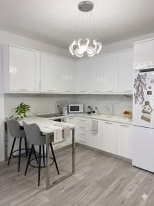 a kitchen with white cabinets and a table and chairs at Tirana, Beautifull Apartament Near Mother Teresa Int Airport in Tirana