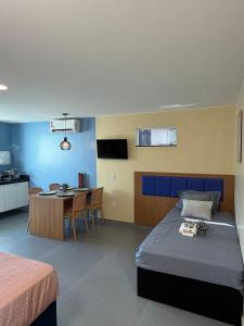 a bedroom with two beds and a table and a kitchen at Studios Caripunas Reformado Localização Central in Belém