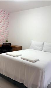 a white bed with two white towels on top of it at Recanto Tarobá in Ponta Grossa