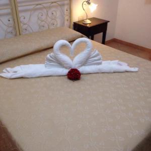 a bed with two towels in the shape of a heart at Abbadia in San Vito lo Capo
