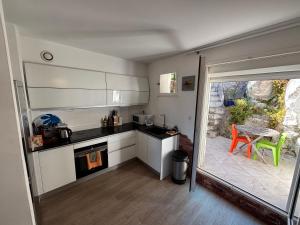 a kitchen with white cabinets and a table and a patio at Parc National des Calanques, LA FLIBUSTE DES GOUDES Maison 2 chambres CLIMATISEE, jardins Jaccuzzi proche plage large vue mer PARKING reserve a l arrivee in Marseille