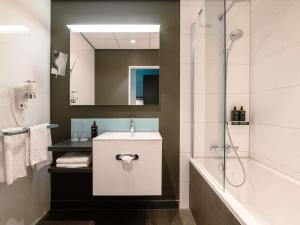 a bathroom with a white sink and a shower at Mercure Hotel Tilburg Centrum in Tilburg