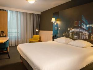 a hotel room with a large bed and a yellow chair at Mercure Hotel Tilburg Centrum in Tilburg +90 photos