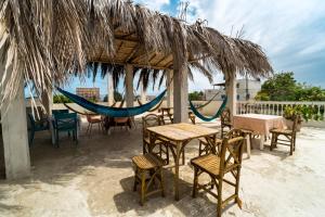eine Terrasse mit Tischen und Stühlen sowie einer Hängematte in der Unterkunft Pangora, habitación privada de Flor de Lis Beach House in Playas