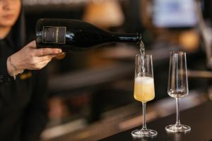 a person pouring a bottle of wine into two wine glasses at VENEZIANA Boutique Hotel Superior in Koper