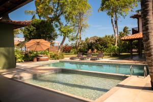 a swimming pool with two chairs and an umbrella at Pousada Villa Tainá - Arraial d'Ajuda, Bahia in Arraial d'Ajuda