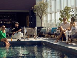 a group of people sitting around a swimming pool at Pullman La Pléiade Montpellier Centre in Montpellier