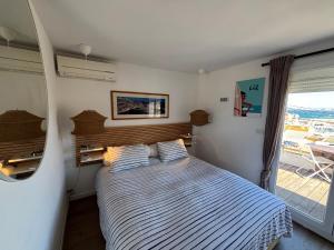 a bedroom with a bed with striped sheets and a window at Parc National des Calanques, LA FLIBUSTE DES GOUDES Maison 2 chambres CLIMATISEE, jardins Jaccuzzi proche plage large vue mer PARKING reserve a l arrivee in Marseille