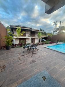 a patio with tables and chairs next to a swimming pool at Dara House apart e eventos com piscina, sauna, Jacuzzi e área gourmet para festas in Cachoeira do Campo