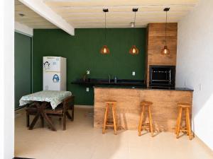 a kitchen with green walls and a counter with stools at Casa Marinho - Pé na praia in Saquarema