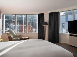 a hotel room with a bed and a chair and windows at Sofitel Luxembourg Europe in Luxembourg