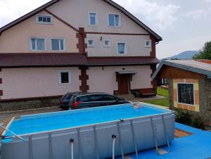 a house with a pool in front of a house at "Різьб'ярська садиба" in Slavske