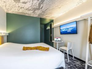 a bedroom with a bed and a tv on the wall at ibis Beaune Centre in Beaune +54 photos