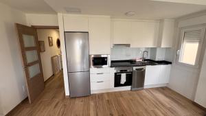 a kitchen with white cabinets and a stainless steel refrigerator at AuraGalega Sagres in Ribeira