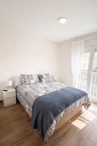 a white bedroom with a bed with a blue blanket at AuraGalega Sagres in Ribeira